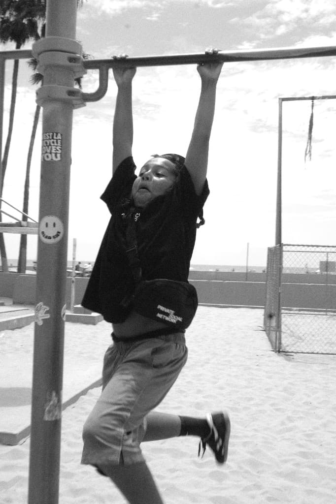 A young man doing a pull-up at the beach.