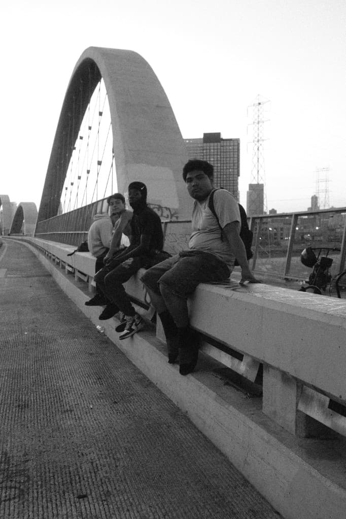 Four young men sitting on a bridge.